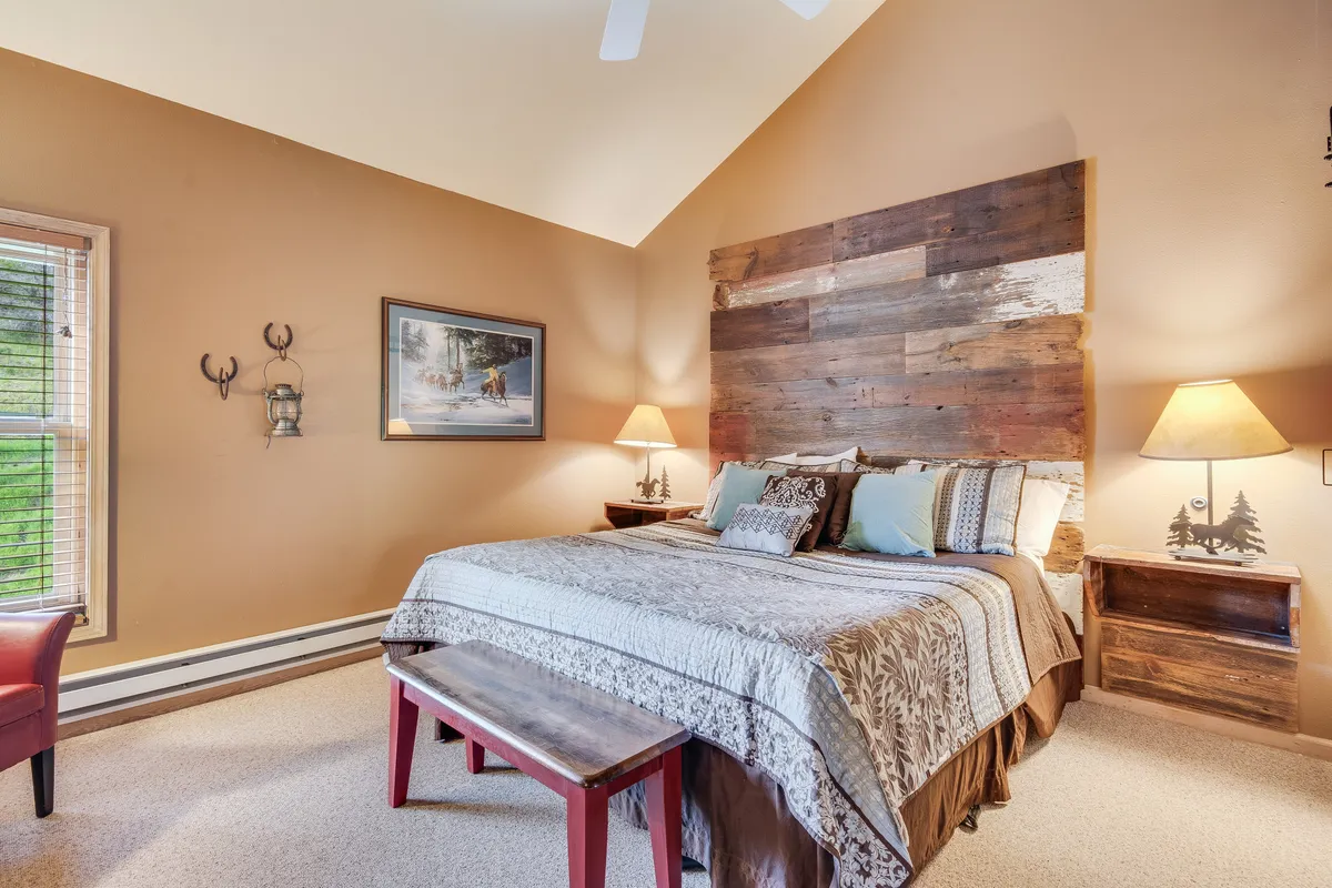 A king bedroom with a wooden headboard, soft decorative pillows, bedside lamps, and wall art. The room radiates warmth and privacy, ideal for recharging after group adventures or time together in shared spaces.