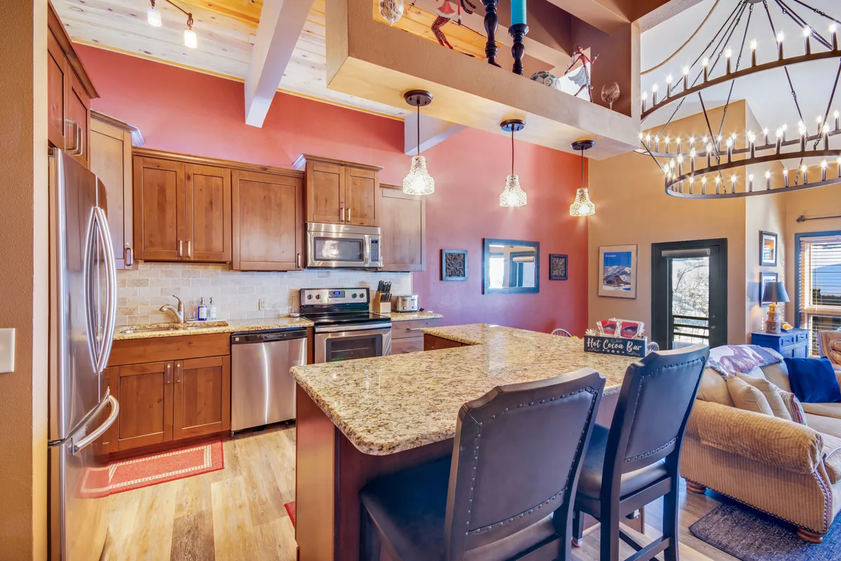 A warm, open kitchen with granite countertops, wooden cabinetry, a chandelier, and a seating area that invites conversation. The modern appliances and layout highlight the recently remodeled space, while natural light and thoughtful design encourage both cooking and socializing.